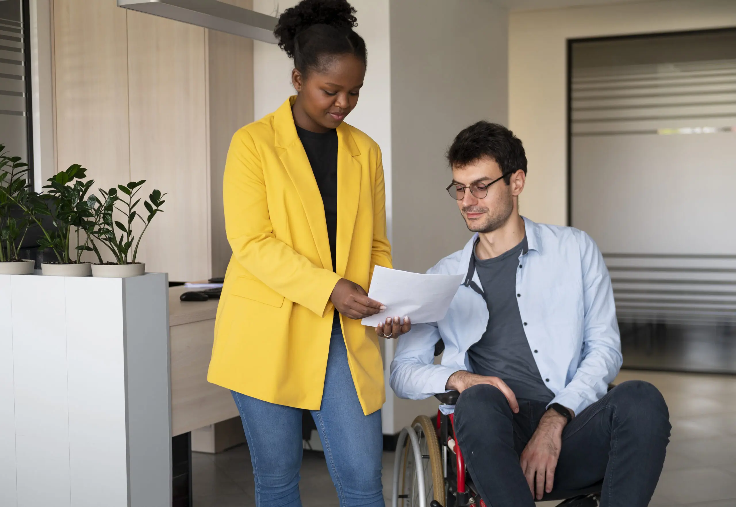 black woman support worker supporting a white man in a wheelerchair