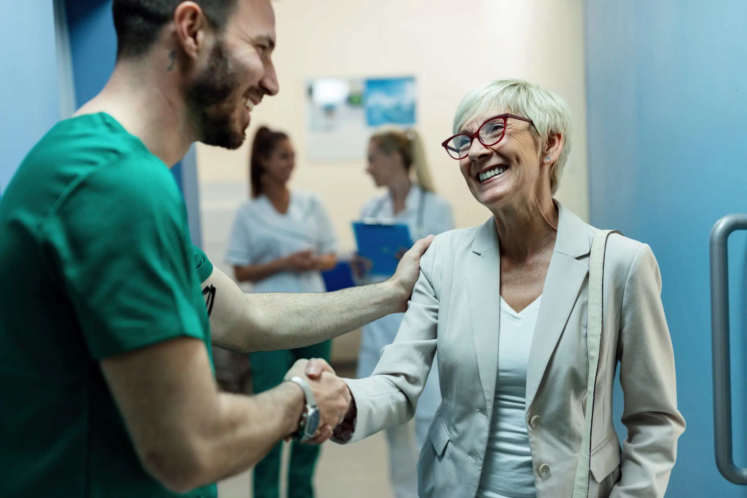 happy health and social care worker shaking hands with a patient