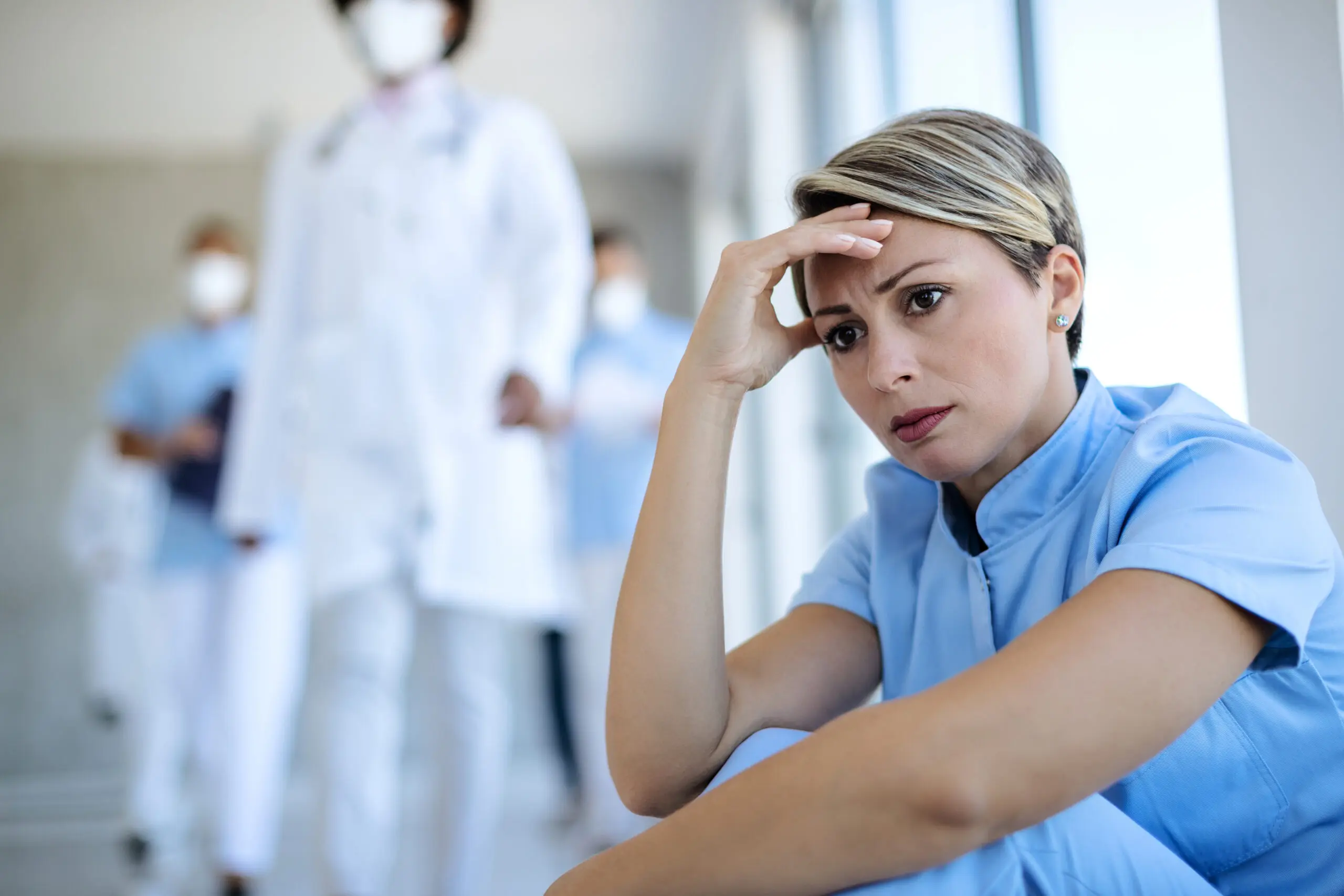 distraught nurse sitting with her head in her hands