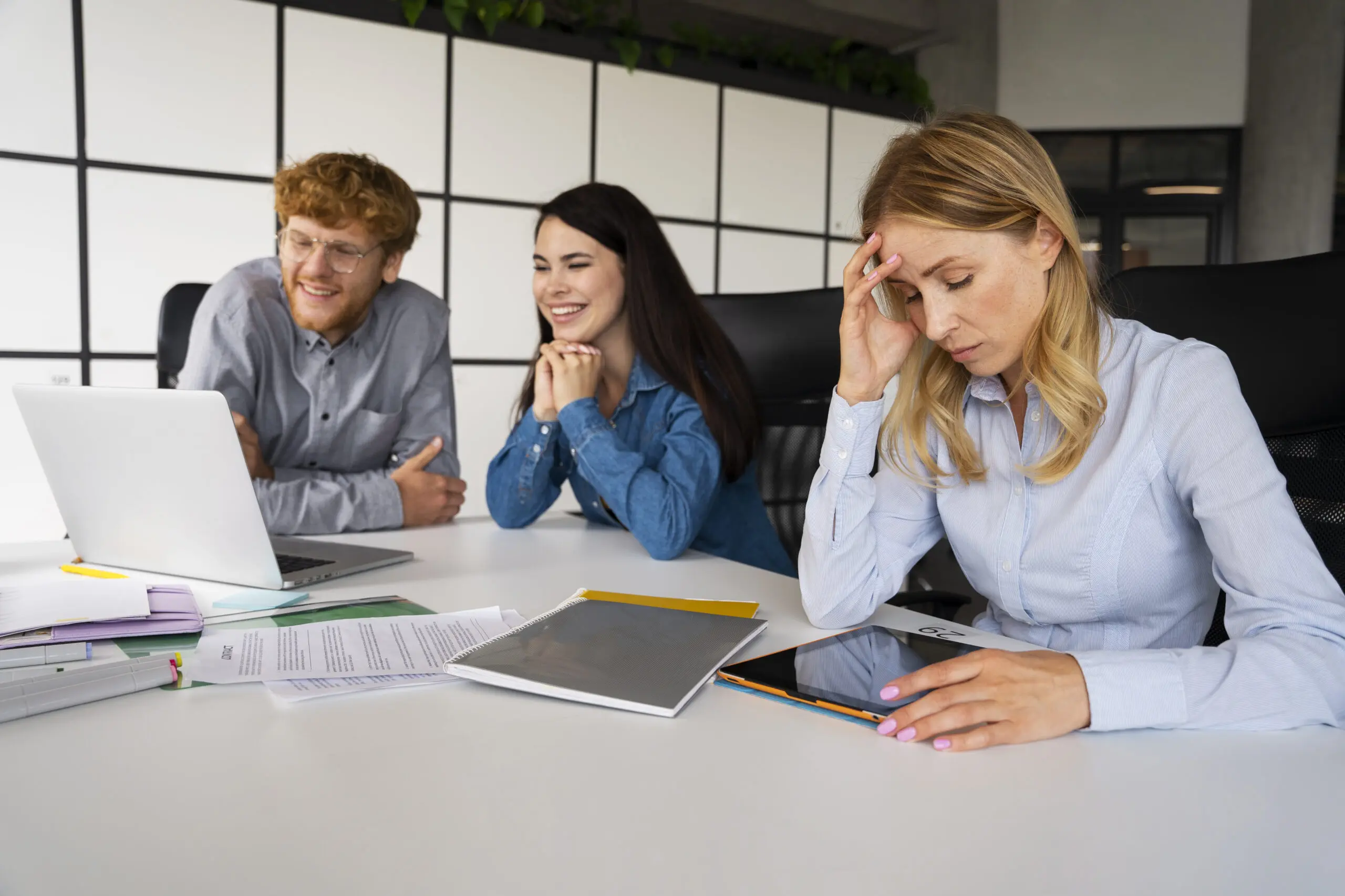 stressed relied on care worker with two colleagues in the background laughing