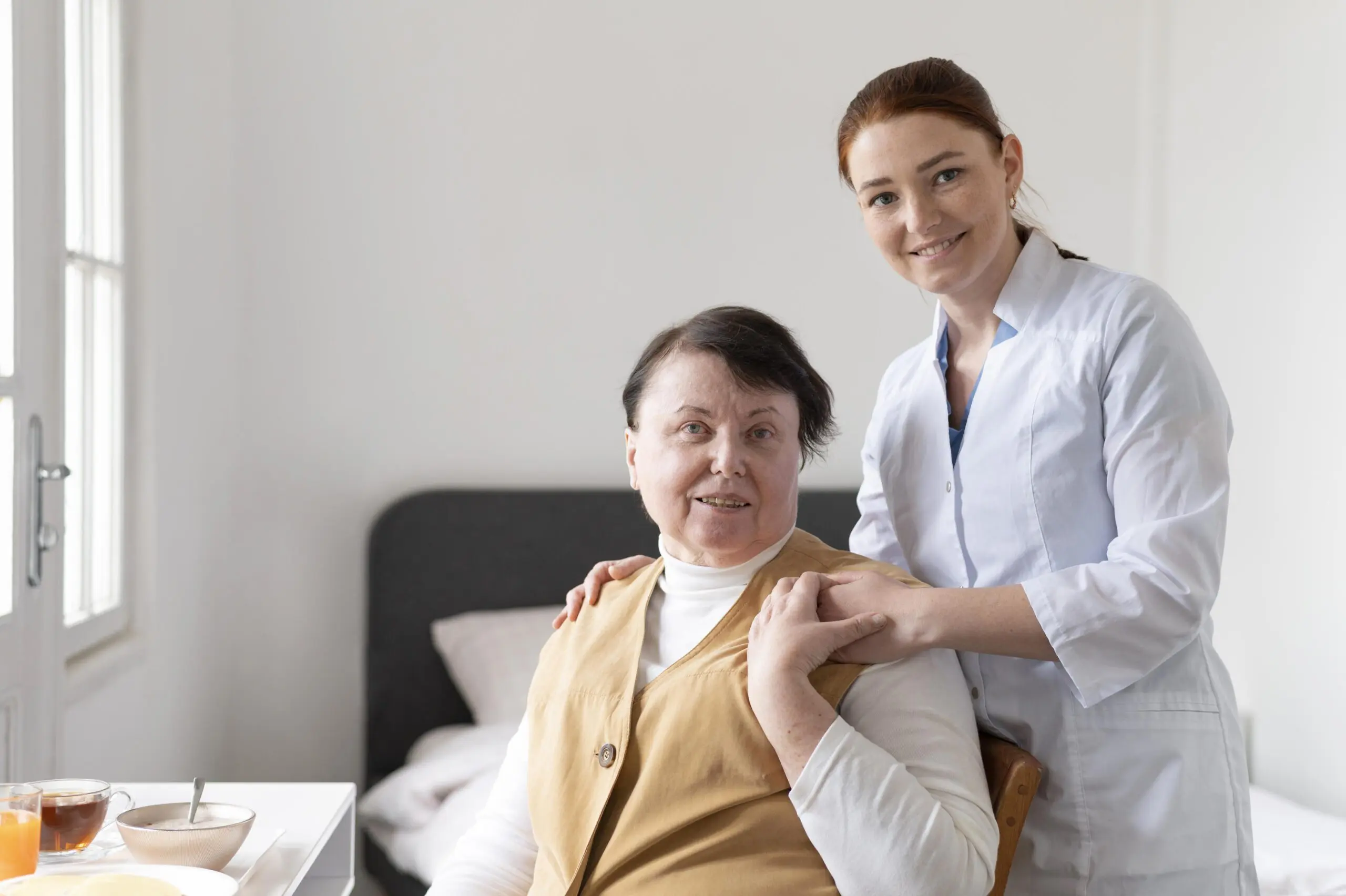 smiling care worker supporting patient with eating breakfast, at her own home