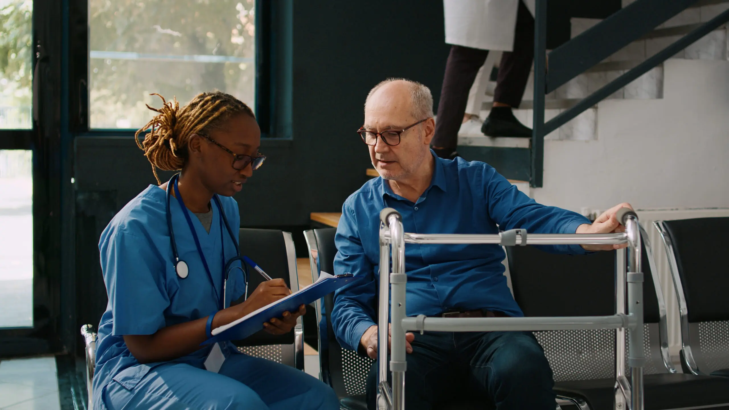 black female support worker assisting elderly white man