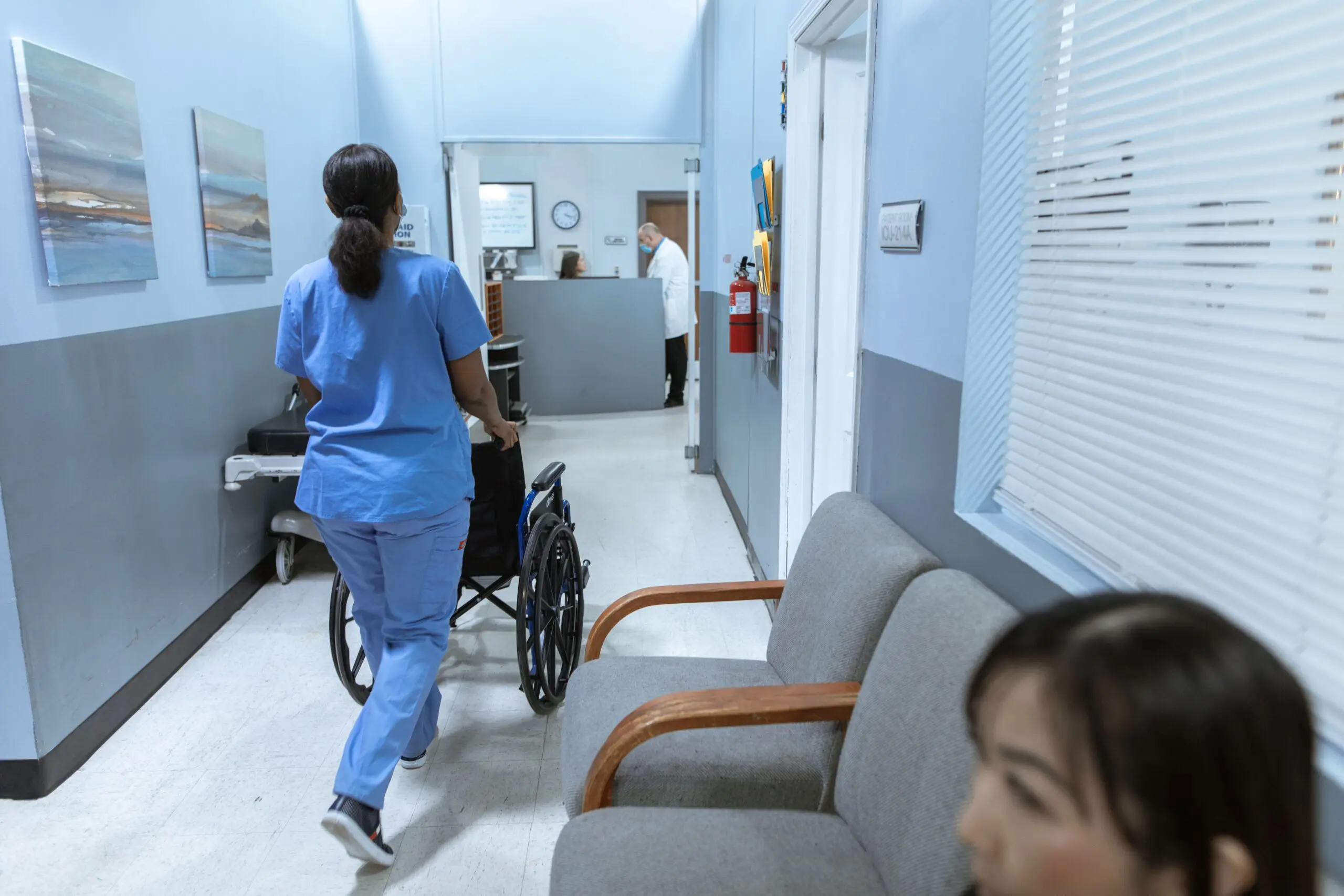 doctor pushing a wheelchair with patients in waiting room
