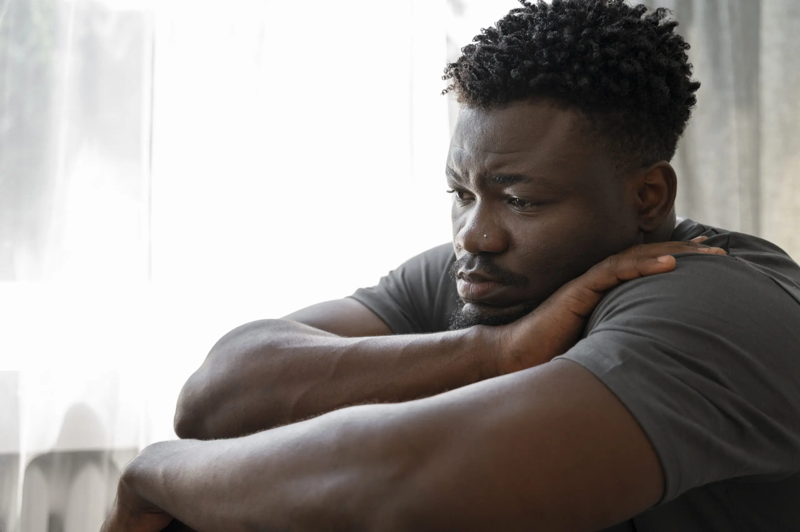 young depressed black man with head in arms