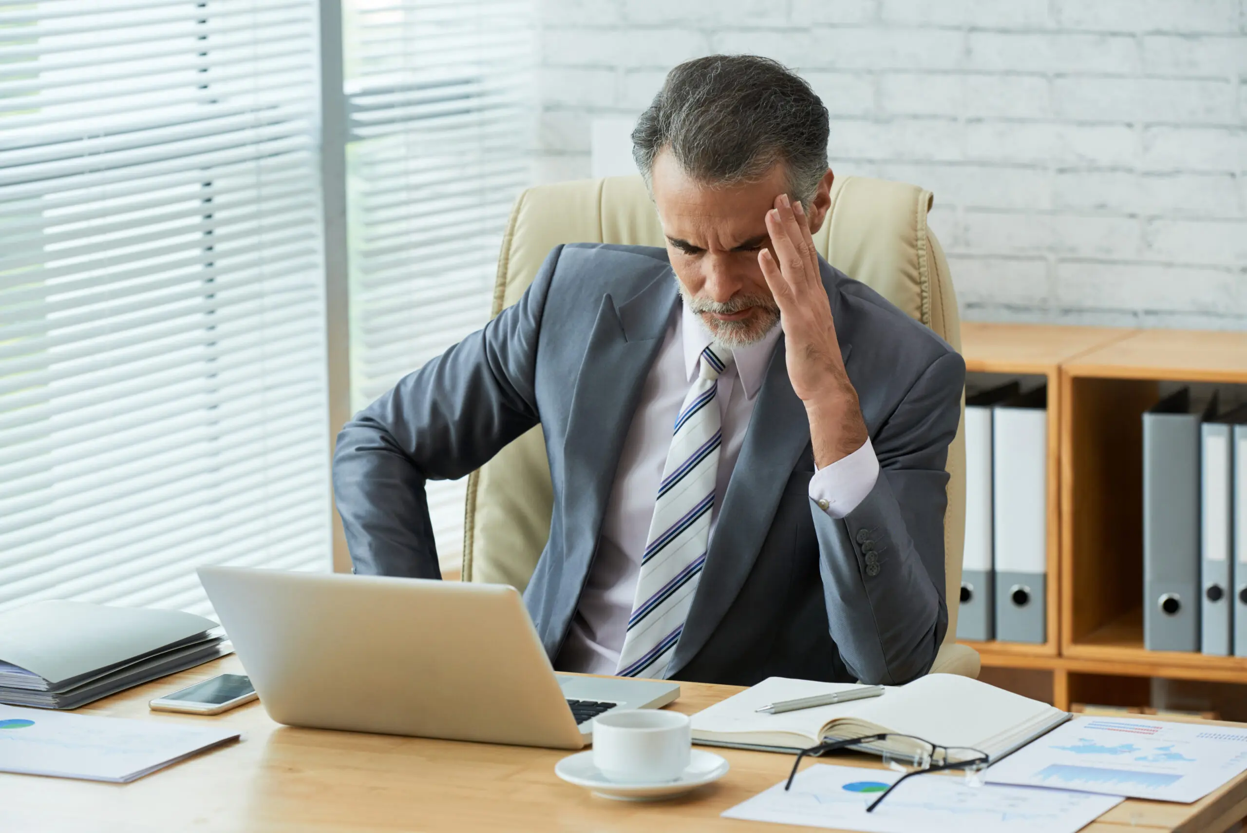 manager slumped over desk due to money concerns
