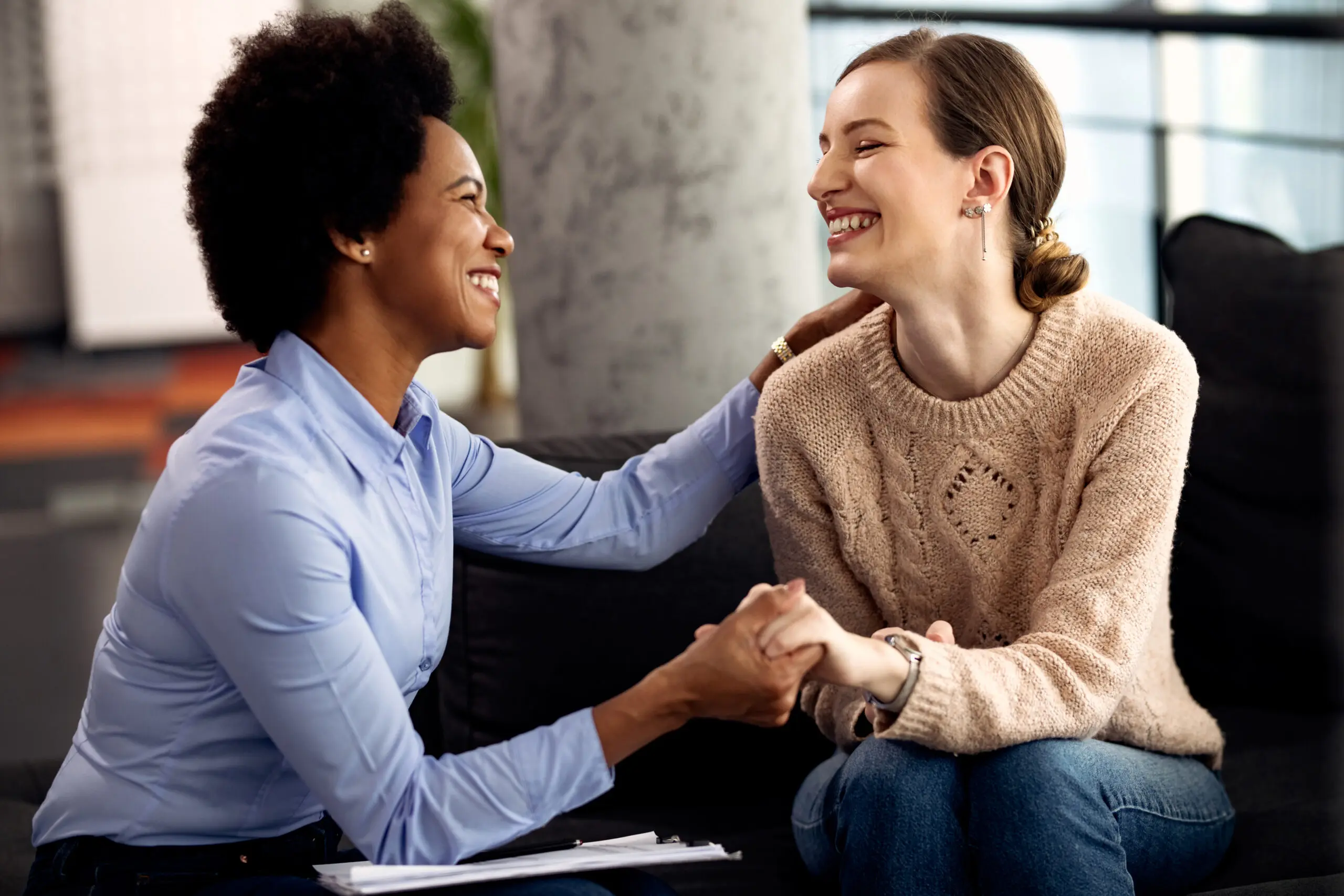 Young happy woman holding hands with her support worker during appointment